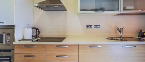 Une cuisine moderne dotée d’appareils électroménagers en acier inoxydable, de meubles en bois et d’un four à micro-ondes encastré.