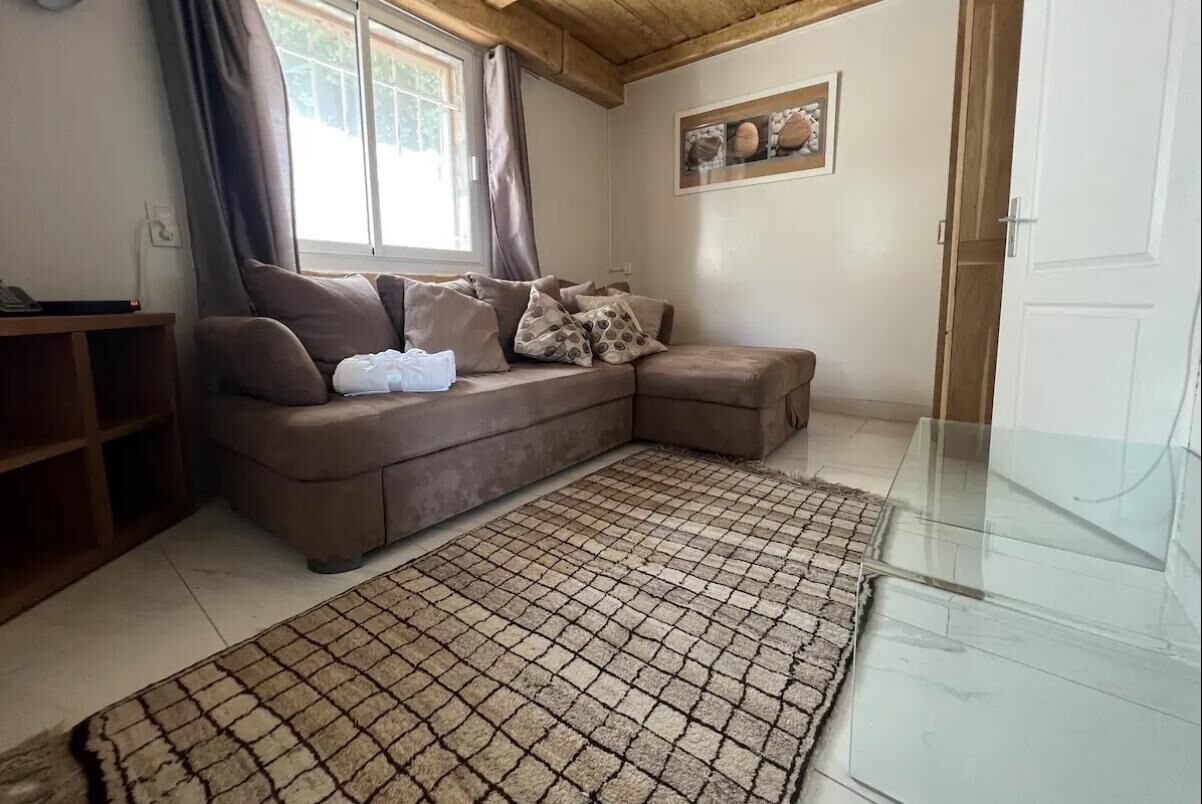 Un salon chaleureux avec un canapé d’angle marron, un tapis à motifs et un plafond en bois.