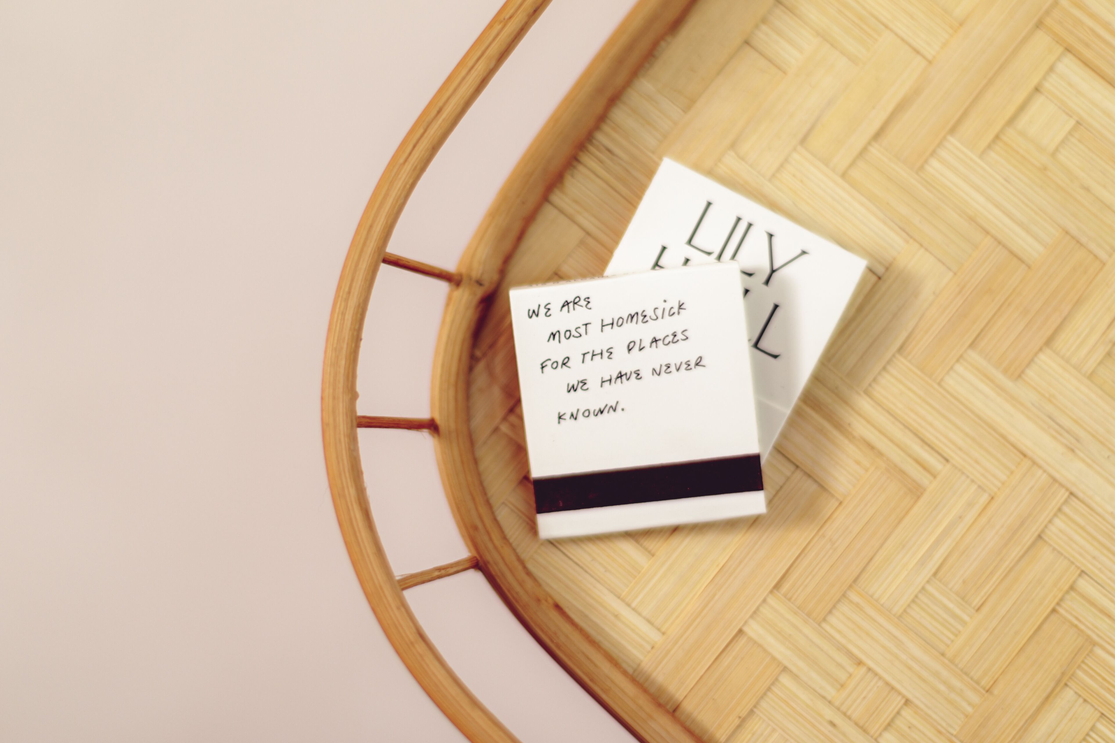 A round wooden table with a woven surface, holding two white cards with black text.