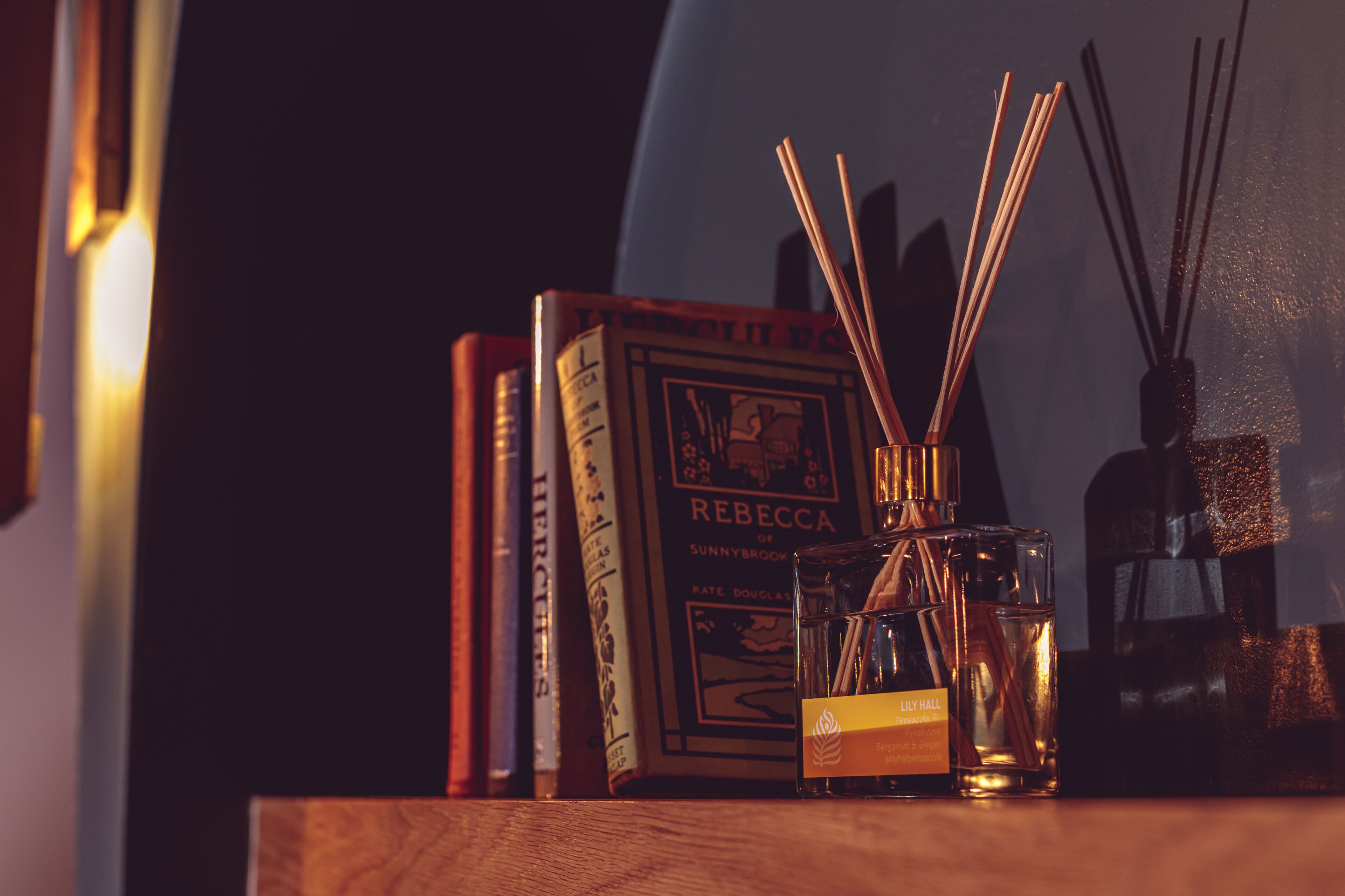 A bookshelf with books and a bottle of perfume.