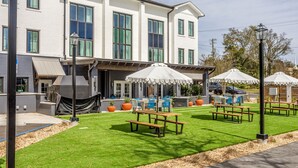 A building with a patio area featuring tables and chairs, a barbecue grill, and a covered seating area. - Lily Hall- A Boutique Hotel (Pensacola)