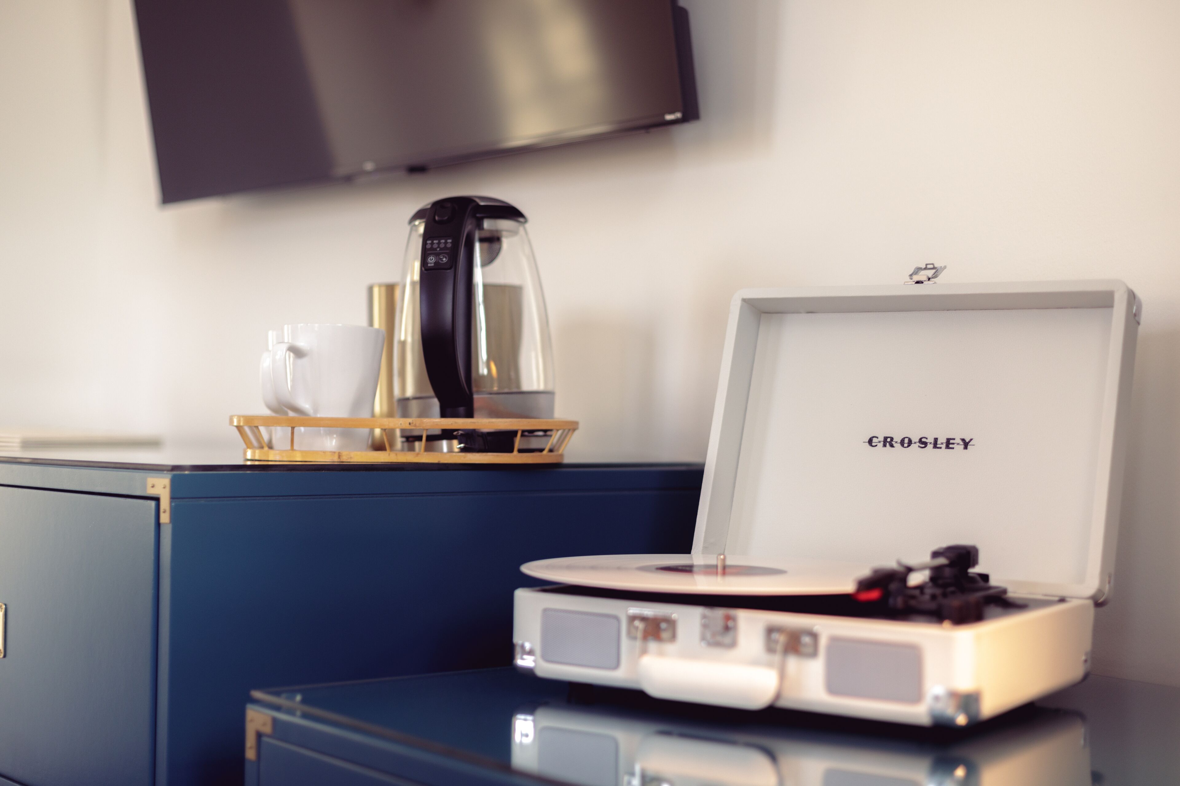 A room with a blue cabinet, a coffee maker, a tray with cups, and a Crosley radio.