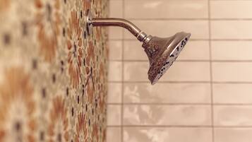 Un pommeau de douche fixé à un mur recouvert de carreaux formant un motif décoratif.