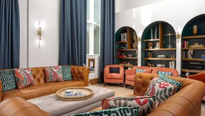 A modern living room with leather sofas, a coffee table, and a bookshelf. - Lily Hall- A Boutique Hotel (Pensacola)