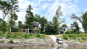 Une maison au bord d’un lac, avec une jetée qui s’avance dans l’eau.