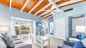 A spacious living area with a high ceiling, a white coffee table, grey sofas, and a blue armchair. - Beautiful Ground Floor 1bed/1.5 Bath Condo with Pool and Beach Access! (Siesta Key)