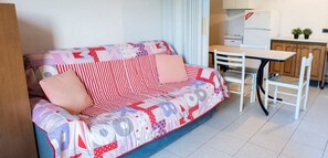 A living room with a sofa, a dining table, chairs, a kitchen area, and a small cabinet. - SE006 - Senigallia, one bedroom apartment on the sea with beach (Senigallia)
