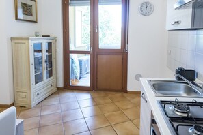 A kitchen with a stove, sink, and a cabinet with glass doors.