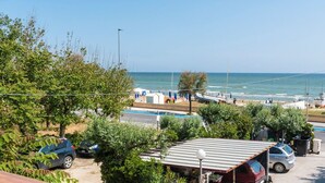 Eine Küstenansicht mit geparkten Autos, einem Strandbereich und Booten.