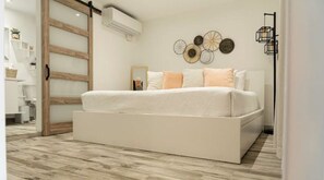 A modern bedroom with a large bed, a sliding barn door, and decorative wall art.