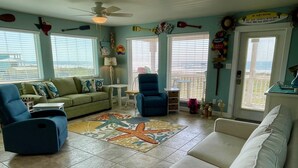 A living room with a green sofa, blue armchairs, a white couch, and a starfish-patterned rug. - Beachgate Condo Suites And Hotel 231+232+233 3 Bedroom Condo (Port Aransas)