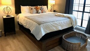 A neatly made bed with a black headboard, two bedside lamps, and a wicker chair by the window. - Cozy Family & Dog 4 Bedroom, 2 Bathroom Home (Harker Heights)