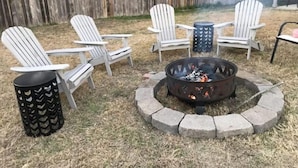 A backyard with a fire pit, four Adirondack chairs, and a metal trash can. - Cozy Family & Dog 4 Bedroom, 2 Bathroom Home (Harker Heights)
