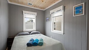 A bedroom with a bed, two windows, and a small picture on the wall. - 2 COTTAGES WITH A SHARED DECK 4 BEDROOMS, 2 BATHS, SLEEPS 8. VACATION TOGETHER (Seaside Heights)