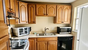 A kitchen with wooden cabinets, a double sink, a microwave, an oven, and a dishwasher.