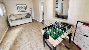 A room with a foosball table, a sofa, and a framed picture on the wall.