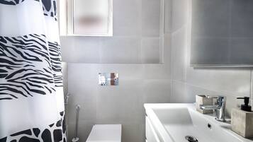 A modern bathroom with a white sink, a toilet, and a shower.