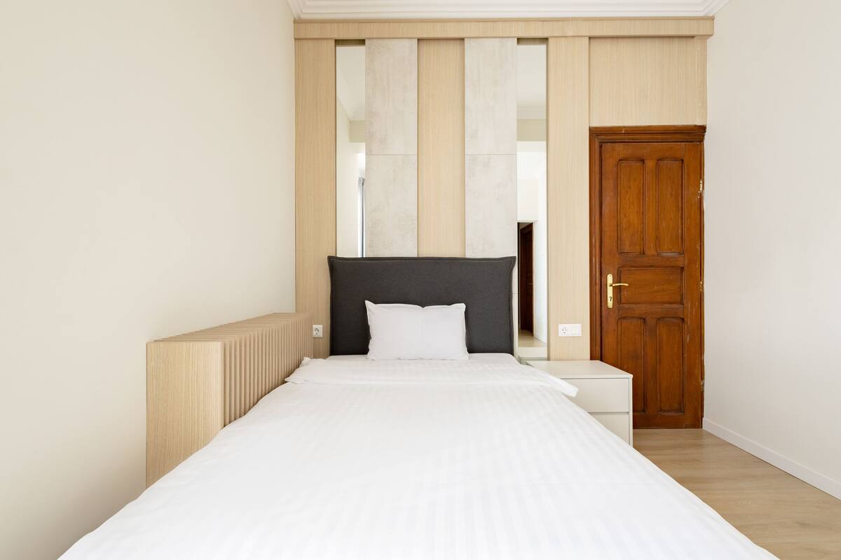 A bedroom with a bed, a wooden door, and a radiator.