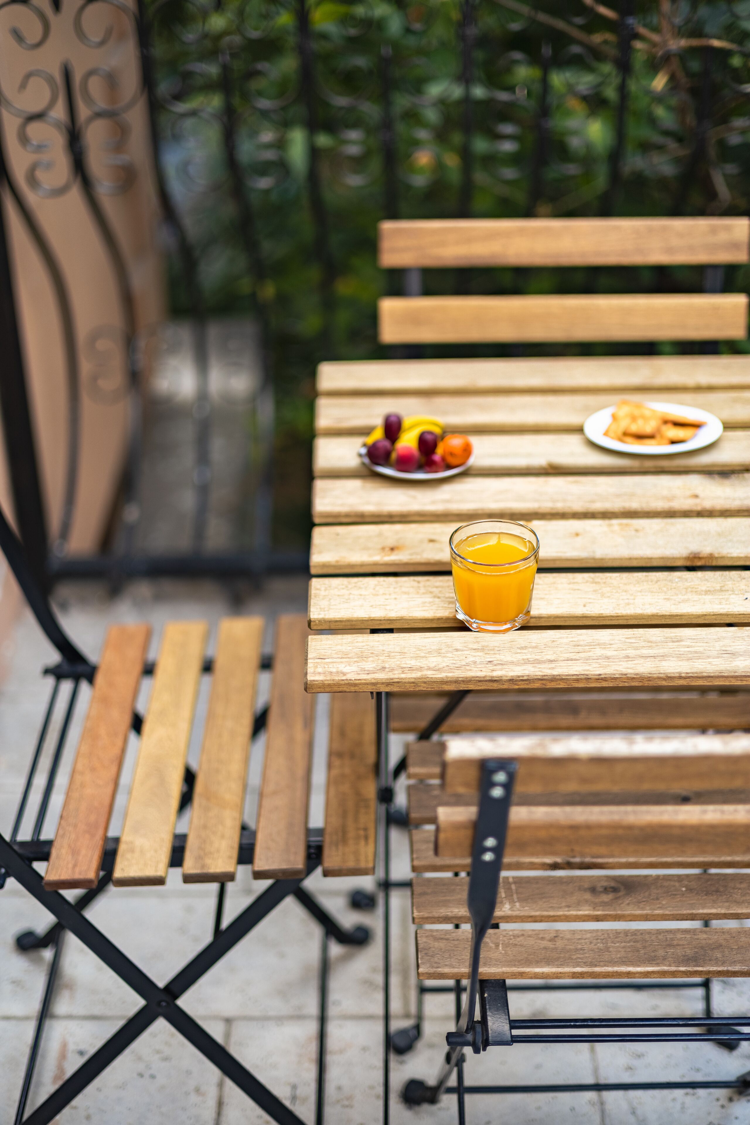 A wooden table with a glass of orange juice and plates of fruit and toast.