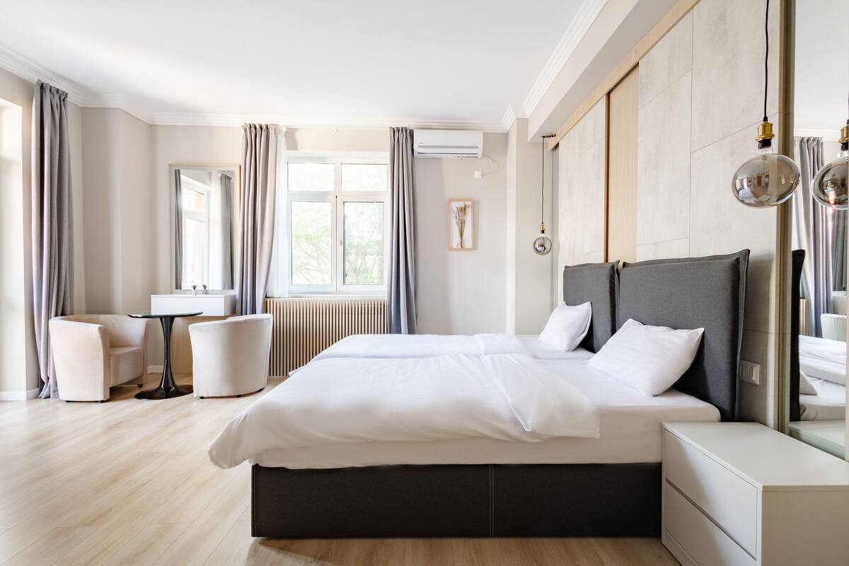 A modern hotel room with a large bed, a small table, and a sofa.