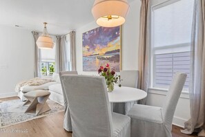 Enjoy meals in a stylish dining area with a round table, comfortable chairs, and a vibrant abstract art piece above.