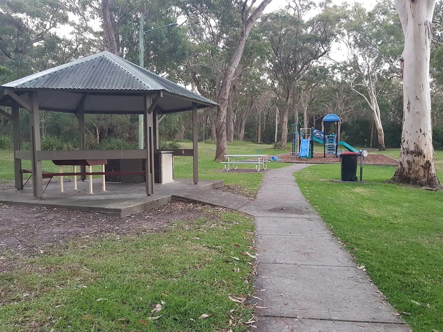 A park with a gazebo, picnic tables, a playground, and a walking path.
