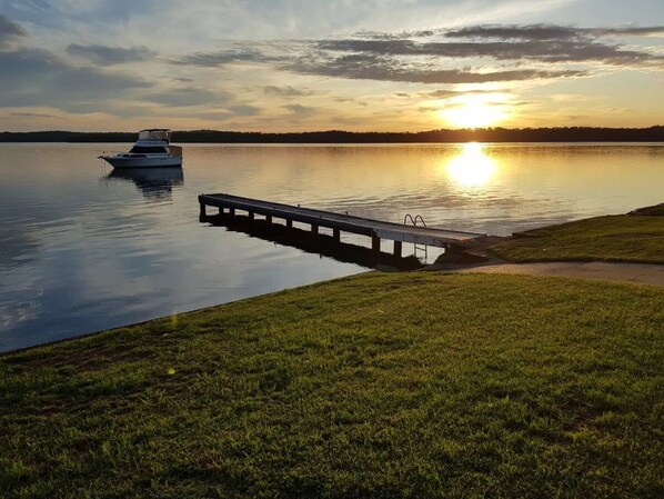 A boat docked at a pier extending into calm water during sunset. - "Sunshine On The Water" Absolute Waterfront & Jetty.  Paradise at your doorstep. (Sunshine)