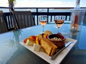 A table with a glass of wine, a bowl of dip, crackers, and cheese. - "Sunshine On The Water" Absolute Waterfront & Jetty.  Paradise at your doorstep. (Sunshine)