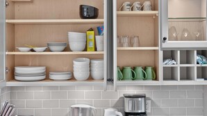 A kitchen with white tiled backsplash, open cabinets with dishes and kitchenware, and a coffee maker on the counter. - Entire 4-Bedroom Garden Level Suite Near UBC/YVR (Vancouver)