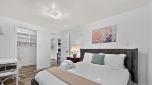 A bedroom with a bed, bedside table, lamp, and a wardrobe. - Entire 4-Bedroom Garden Level Suite Near UBC/YVR (Vancouver)