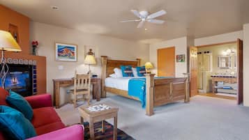Relax in a comfortable room with a bed, desk, and sofa, featuring a fireplace and a bathroom with a vanity and sink.