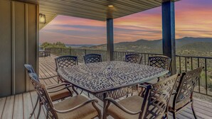 A covered outdoor patio with a table and chairs, overlooking a scenic landscape.
