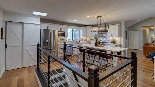 A modern kitchen with white cabinetry, a central island, and a chandelier.