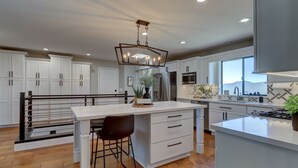 A modern kitchen with white cabinetry, a central island, and a large window offering a view.