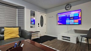 En moderne stue med et fladskærms-tv på væggen, en sofa, et sofabord og et tv-møbel med en lænestol.