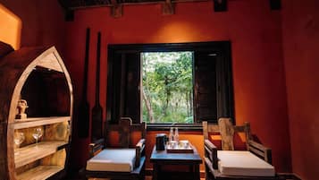 Una habitación acogedora con un barril de madera, una mesa con una bandeja y un ventanal con vistas a los árboles.