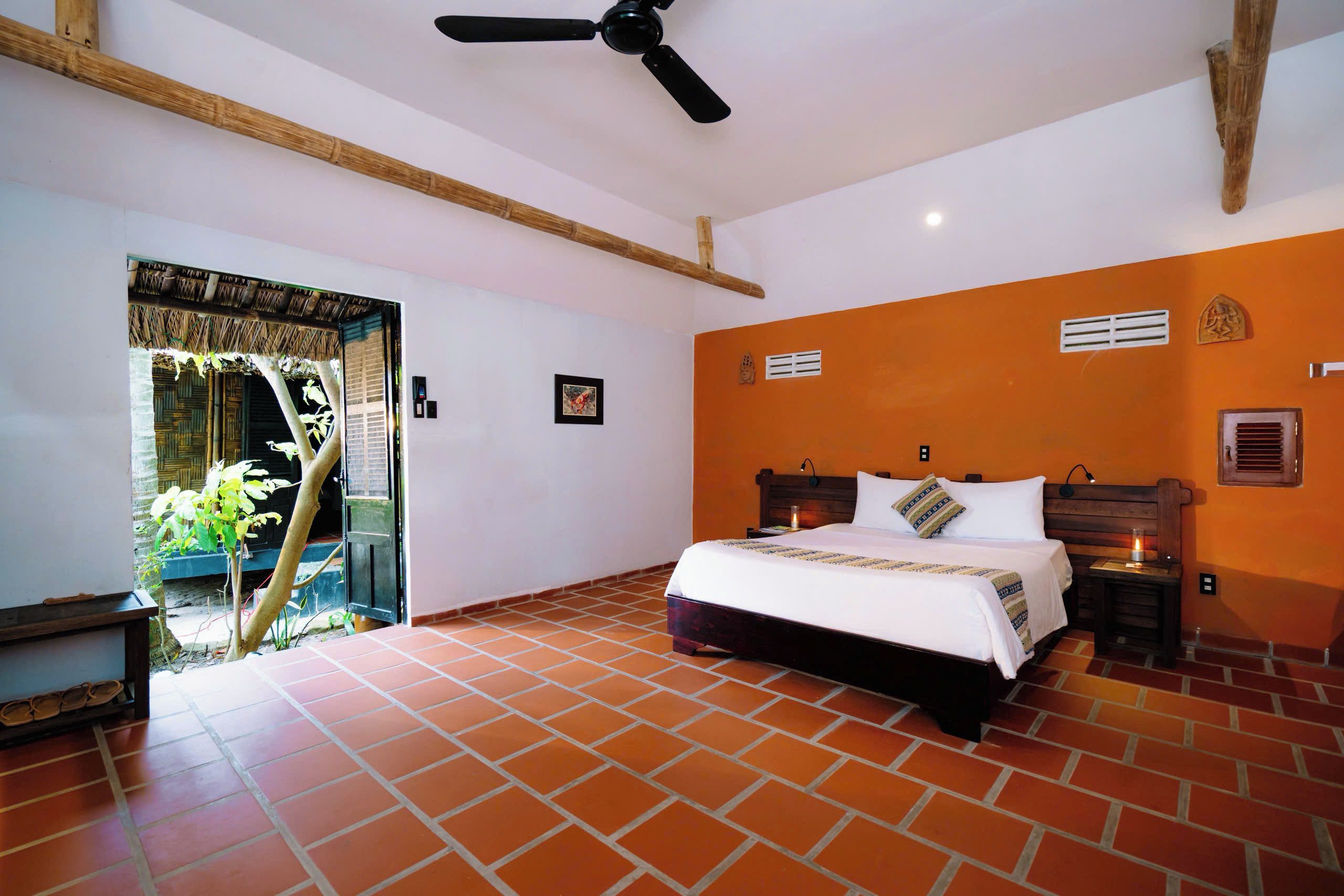A bedroom with a bed, a ceiling fan, a nightstand, and a window with a view of greenery.
