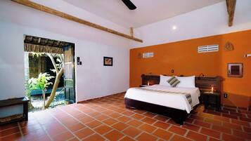 A bedroom with a bed, a ceiling fan, a nightstand, and a window with a view of greenery.