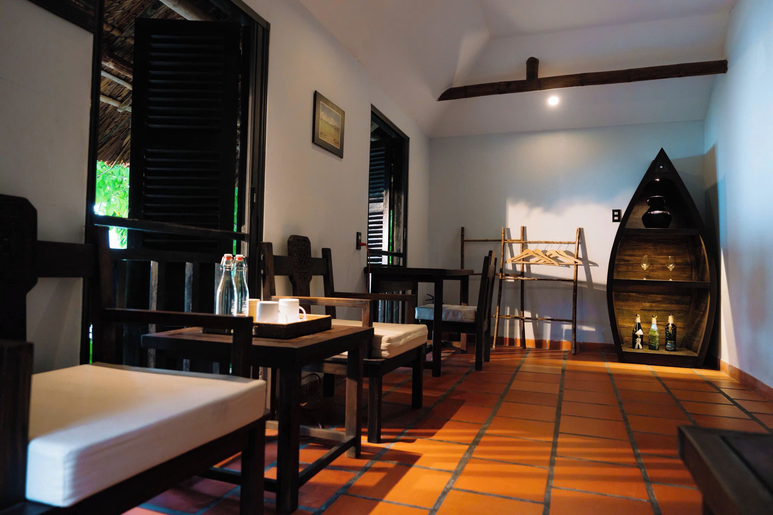 Una habitación acogedora con muebles de madera, suelo de baldosas y un estante original en forma de barco con botellas.