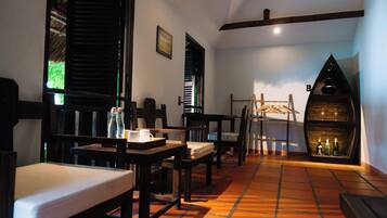 Una habitación acogedora con muebles de madera, suelo de baldosas y un estante original en forma de barco con botellas.