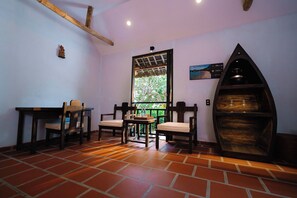 A room with a tiled floor, a wooden table with chairs, a window with a view of trees, and a wooden shelf with a pot. - Whale Island Resort (Nha Trang)