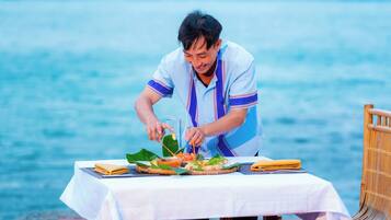 Una persona preparando comida en una mesa con vista al mar.