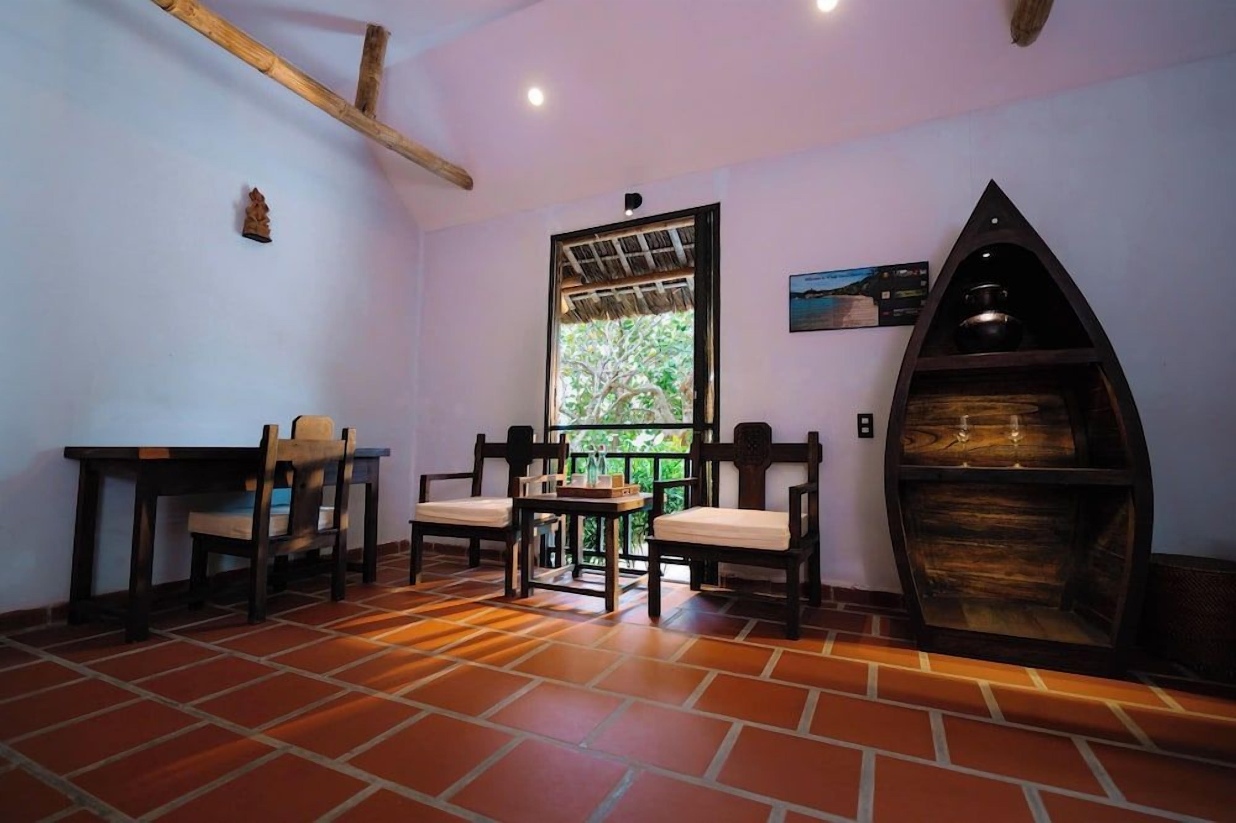 Una habitación con piso de baldosas, una mesa con sillas, un ventanal con vistas y un estante de madera.