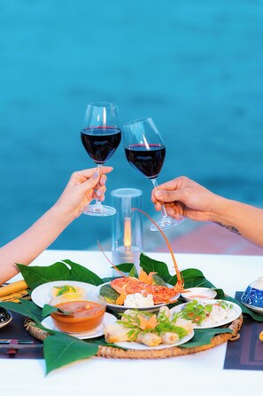 A table with a variety of dishes, including seafood and a bowl of soup, set against a blue background. - Whale Island Resort (Nha Trang)