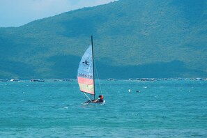 A sailboat with a colorful sail on a calm sea, with a mountainous backdrop. - Whale Island Resort (Nha Trang)