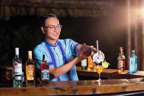 A bartender preparing a drink with various bottles of alcohol on the counter.