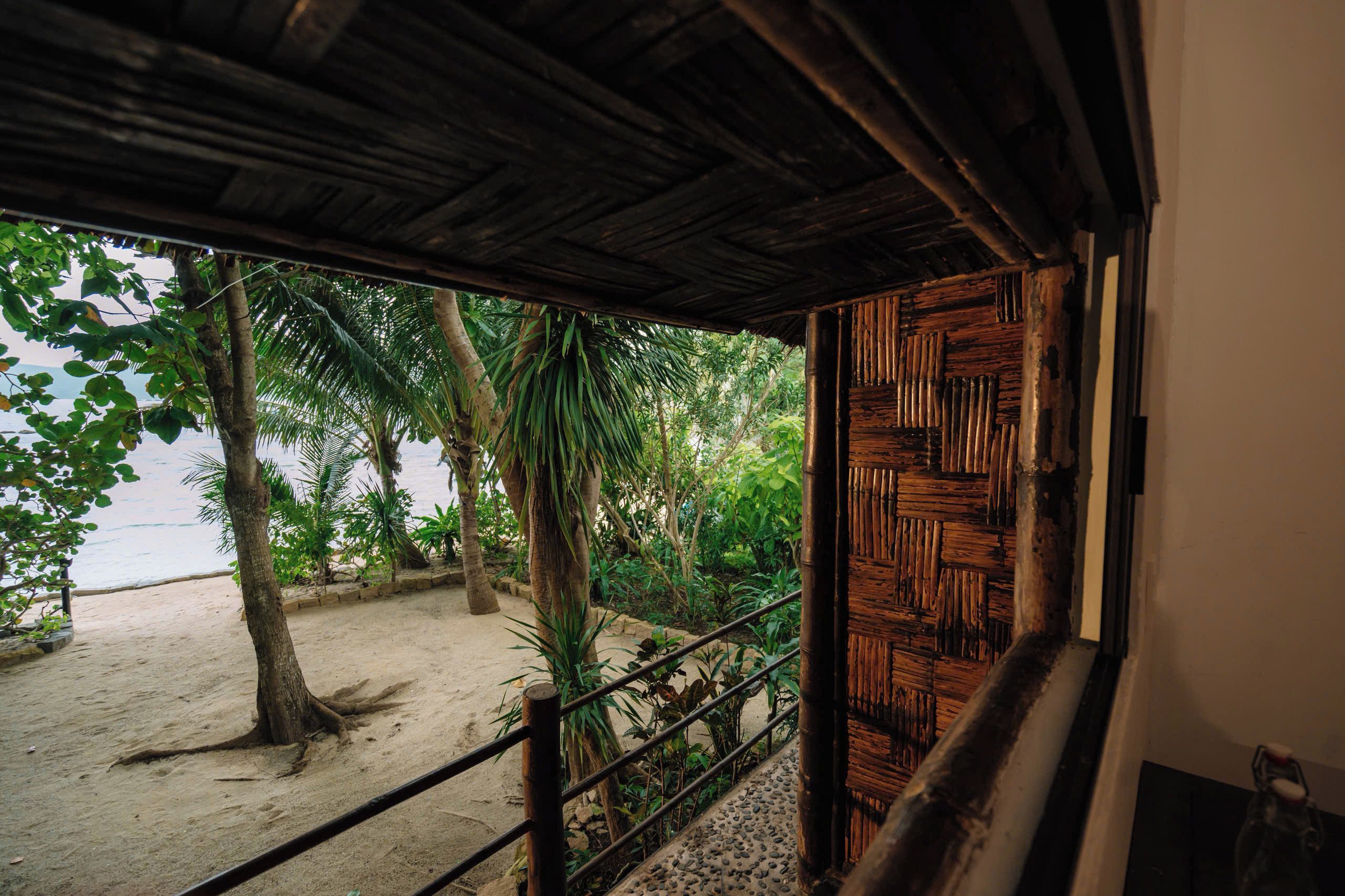 A wooden staircase leading to a beach with palm trees and a sandy shore.