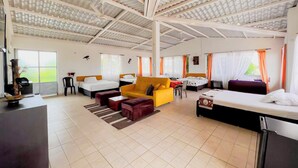 A spacious hotel room with a large bed, a yellow sofa, a dining table, and a kitchen area. - Altos de agua blanca  (Tauramena)