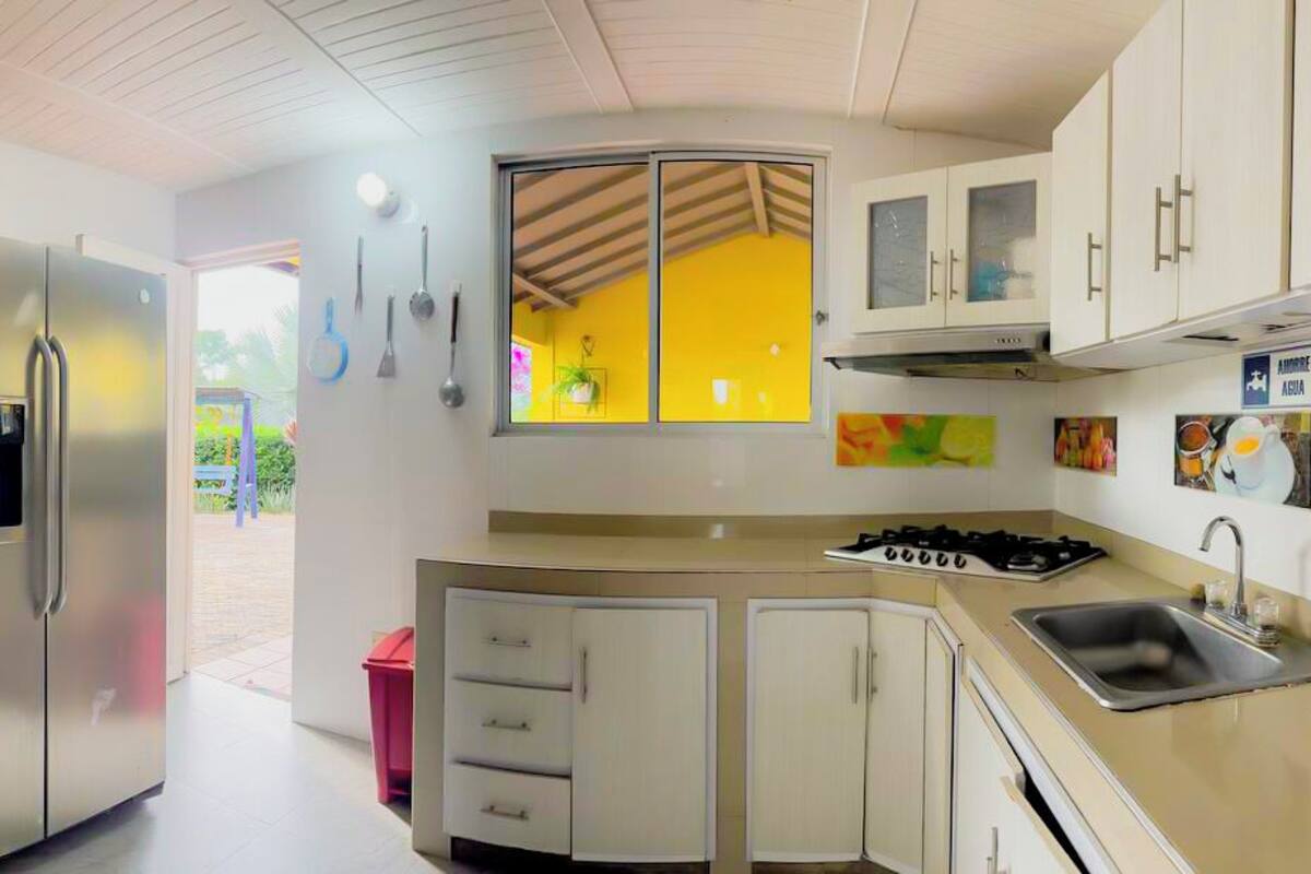 A compact kitchen with a refrigerator, sink, stove, and cabinets.