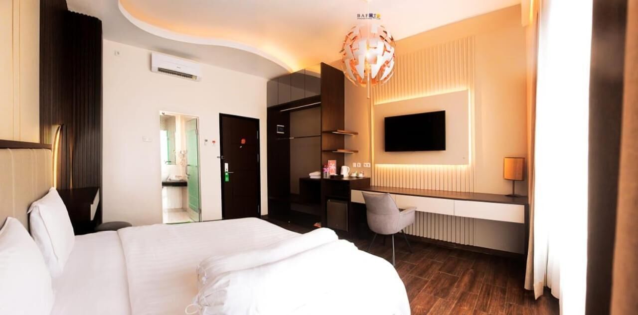 Een hotelkamer met een bed, een bureau, een stoel, een televisie en een moderne kroonluchter.